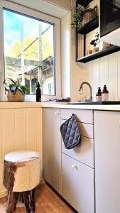 a kitchen with a sink and a window and a stool at Leilighet midt i Sokndal sentrum in Sokndal