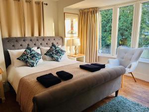 ein Schlafzimmer mit einem großen Bett und einem weißen Stuhl in der Unterkunft Flora Cottage, in the heart of the city in Salisbury