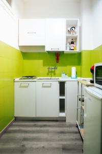 a kitchen with white cabinets and green walls at Casale City in Casale Monferrato +9 photos