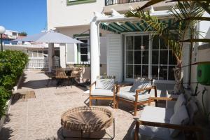 a patio with chairs and tables and an umbrella at Pura Vida by Maspalomas Holiday Villas in Pasito Blanco