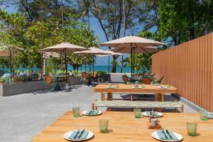 two wooden tables with chairs and umbrellas on a patio at Courtyard by Marriott Phuket, Patong Beach Resort in Patong Beach +188 photos