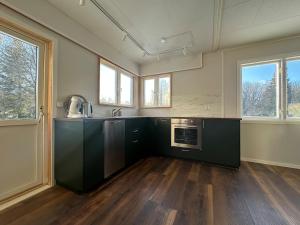 a kitchen with black cabinets and a sink and windows at Hus Sebbe in Nora