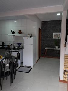 a kitchen with a white refrigerator and a table at Casa em Vivendas - Pedra Azul in Domingos Martins