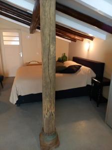 a bedroom with a bed and a wooden pole at Kleine Buurt aan het Water in Lettelbert +2 photos
