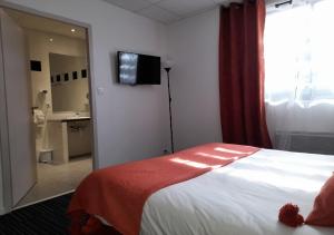 a hotel room with a bed and a television on the wall at Les Jardins de L'Ocean - Climatisé in Biscarrosse-Plage