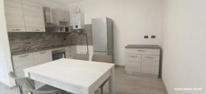 LNI Ferrera في Cunardo: مطبخ به طاولة بيضاء وثلاجة