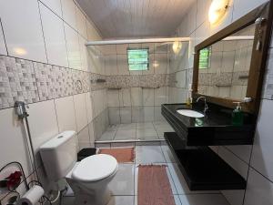 a bathroom with a toilet and a sink and a mirror at Chácara portal do dragão casa completa para 6 pax in Paraty +18 photos