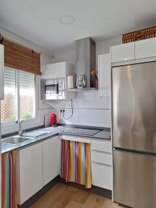 a kitchen with white cabinets and a stainless steel refrigerator at Casa Kiwi Playa a 50 metros in El Palmar