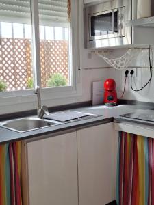 a kitchen with a sink and a microwave at Casa Kiwi Playa a 50 metros in El Palmar