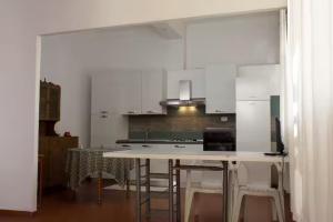 a kitchen with white cabinets and a table and chairs at A pochi passi dalla Spiaggia in Portixeddu