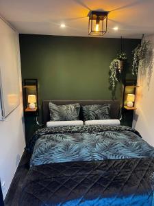 a bedroom with a bed with a green wall at CAPFUN luxe chalet Onthaasten op de Veluwe za tm za in Doornspijk +19 photos