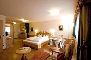 サン・カッシアーノにあるCiasa Anteriolのベッドとテーブルが備わるホテルルームです。