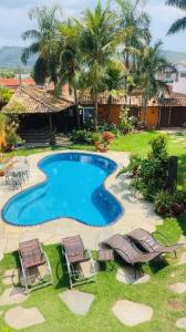 - une vue sur la piscine avec des chaises et une maison dans l'établissement Casa no Centro de Tinguá, à Nova Iguaçu