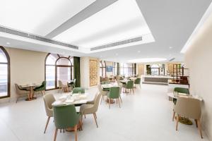 a dining room with tables and chairs and windows at Grand Millennium Al Haram Hotel in Medina
