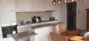 a kitchen with white cabinets and a table and a dining room at Appartement Bootsman prachtig zicht, groot zonnig terras, garage, fietsenberging OOSTENDE FIETSSTAD - ENSORSTAD in Ostend +14 photos