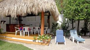 a patio with chairs and a table and a straw umbrella at Villas Mercedes in Zihuatanejo