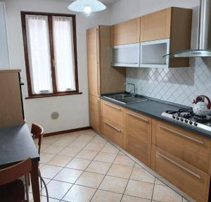 eine Küche mit Holzschränken und einem Herd mit Backofen in der Unterkunft La Casa del Vicolo in Toscolano-Maderno