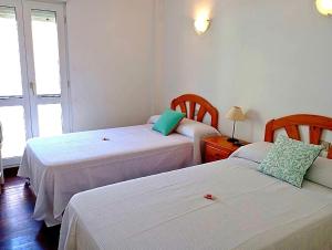 a room with two beds and a table with a lamp at 1ª línea playa de Silgar en Sanxenxo, a 20 pasos in Sanxenxo