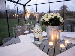 a table with a bottle of wine and flowers and candles at Unik villa med utsiktstorn, orangeri och badtunna in Lysekil