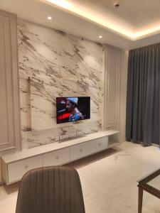 a living room with a tv on a marble wall at Leela Residence, Bhartiya City in Bengaluru