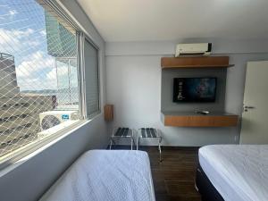 a bedroom with a bed and a window with two stools at Apartamento novo, moderno, completíssimo à beira mar in Santos +22 photos