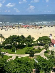 a beach with people on the sand and the ocean at Apartamento novo, moderno, completíssimo à beira mar in Santos