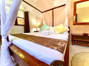 a bedroom with a bed with white sheets and pillows at Samsara Beach House in Kiganga