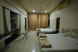 a hotel room with two beds and a television at Hotel Shubhkarta in Akola