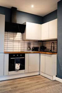 una cucina con mobili bianchi e un forno a piano cottura di Stunning 2 Bedroom Beach Apartment With Garden a Rhos-on-Sea