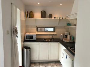 una pequeña cocina con armarios blancos y microondas en BY BABS guesthouse Bergen nh, en Bergen