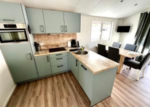 a kitchen with green cabinets and a sink and a table at Beach Chalet- Sauna inklusive Kinder und Hunde Willkommen in Scharbeutz