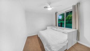 Un dormitorio blanco con una cama y una ventana. en Blue Willow Cottage - Bathurst, en Bathurst