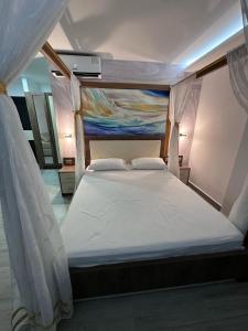 a bedroom with a white bed with a painting on the wall at Hotel Playa Dubai Golden Suite in Cojimíes +10 photos