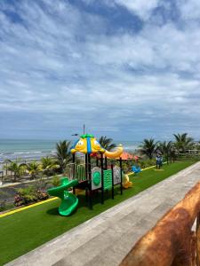 a park with a playground with an umbrella and the ocean at Hotel Playa Dubai Golden Suite in Cojimíes