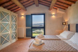 a bedroom with two beds and a large window at Tenuta San Jacopo - Agriturismo in Cavriglia