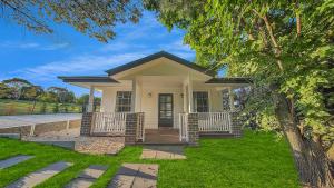 a small white house with a porch and a tree at Blue Willow Estate Bathurst in Bathurst