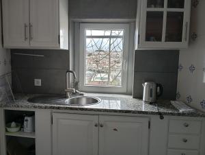 a kitchen counter with a sink and a window at Casa com vista sob a cidade! in Coimbra