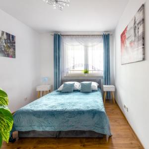 a bedroom with a bed with blue sheets and a window at Apartment BLUE PEARL 2 rooms Down Town 4 persons balcony free parking in Kraków