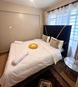 Una gran cama blanca con una almohada amarilla encima. en Romish Luxury Homes, en Nairobi 9 fotos más