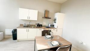 a kitchen with white cabinets and a wooden table at Prime Leeds- Spacious Cinema apartment in Central Station +4 photos