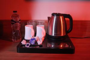 a black coffee maker with cups and a bottle of water at Hotel Regal Palm in Morādābād