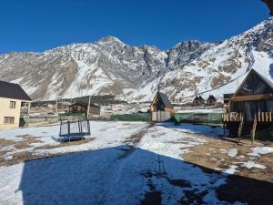 a snow covered mountain with houses and a playground at mood villa kazbegi in Kazbegi
