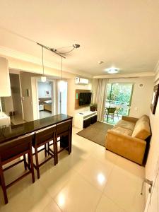 eine Küche und ein Wohnzimmer mit einem Tisch und einer Couch in der Unterkunft Bombinhas Summer Beach -Apartamento Particular in Bombinhas