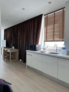 a kitchen with white cabinets and a table and a window at The beach front Condo in Ban Saiyuan (1)