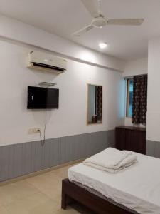 a bedroom with a bed and a tv on the wall at Infinity Rooms D-Mart in Surat