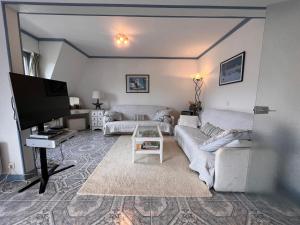 a living room with a couch and a flat screen tv at Duplex en plein centre, 3min plage in Deauville