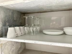 a shelf with glass bottles and plates on it at Plush Bandra West - Luxury 2BHK Apartment & Study in Mumbai +35 photos
