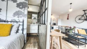 a bedroom with a bed and a kitchen with a table at Au Petit Vélo - Appart Vue sur la Bâtie - Parking Gratuit & Calme - Vienne in Vienne