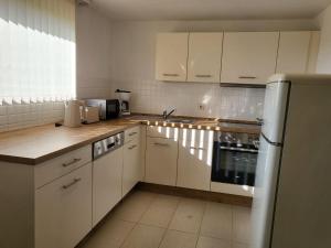 a kitchen with white cabinets and a sink and a refrigerator at Ferienwohnung Irina Legoland ca 30 km in Gerstetten