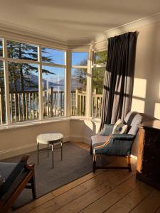 a living room with a couch and chairs and windows at The Sheiling in Saint Fillans